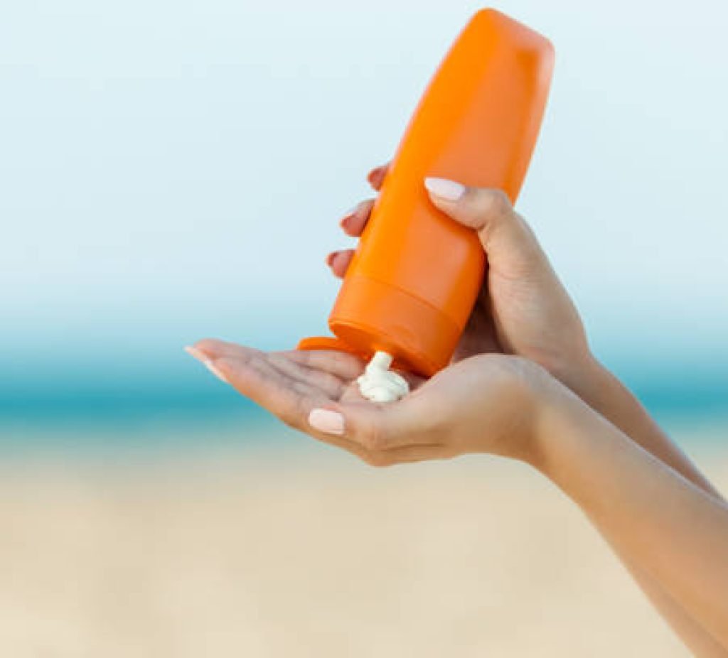 Woman hand apply sunscreen on the beach